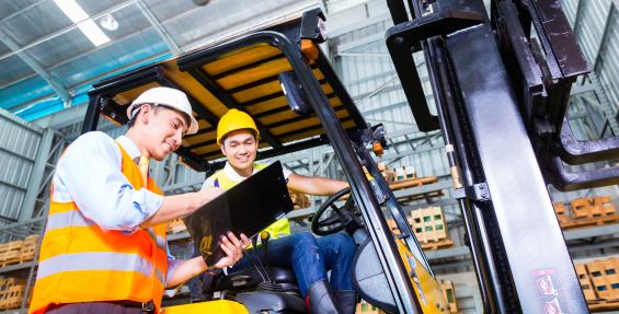 two people talking, one is sitting on a forklift